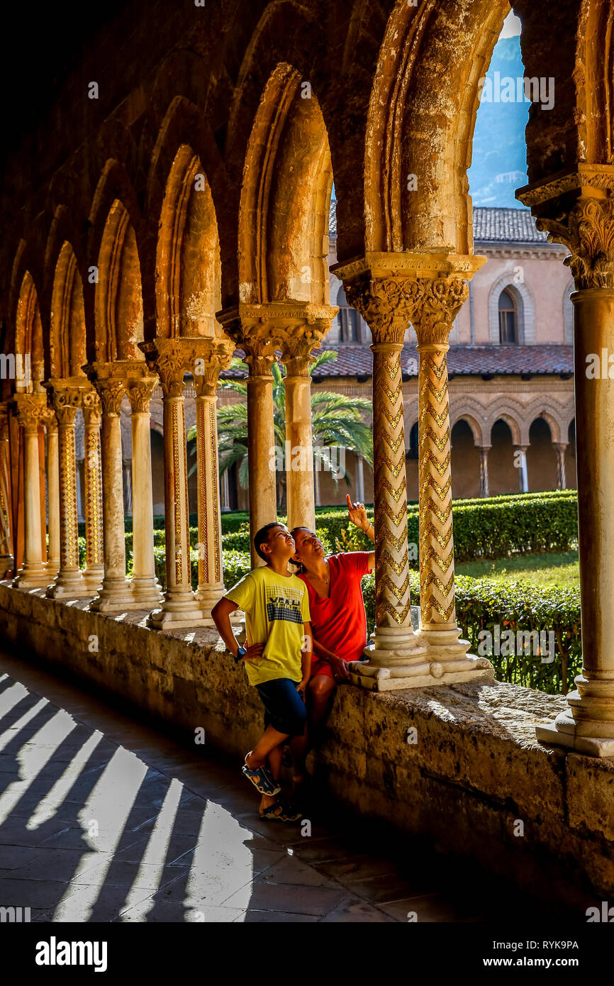 12-year-old boy with his mother in the cloister of Monreale cathedral, Sicily (Italy). Stock Photo