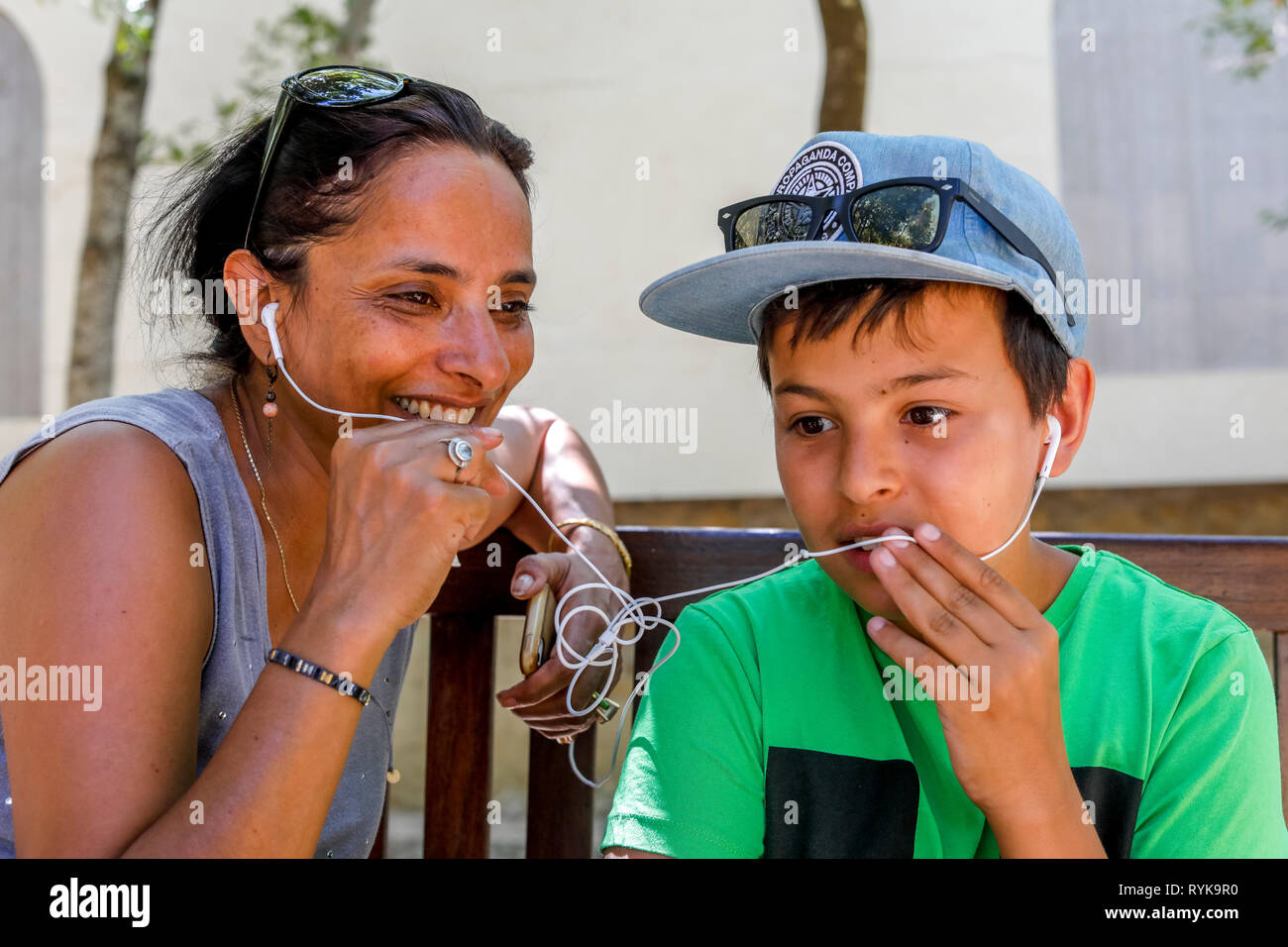Mother and son having a cell phone conversation and sharing earphones in Sicily (Italy). Stock Photo