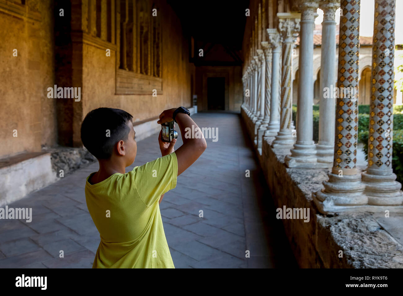 12-year-old boy taking a photograph in the cloister of Monreale cathedral, Sicily (Italy). Stock Photo