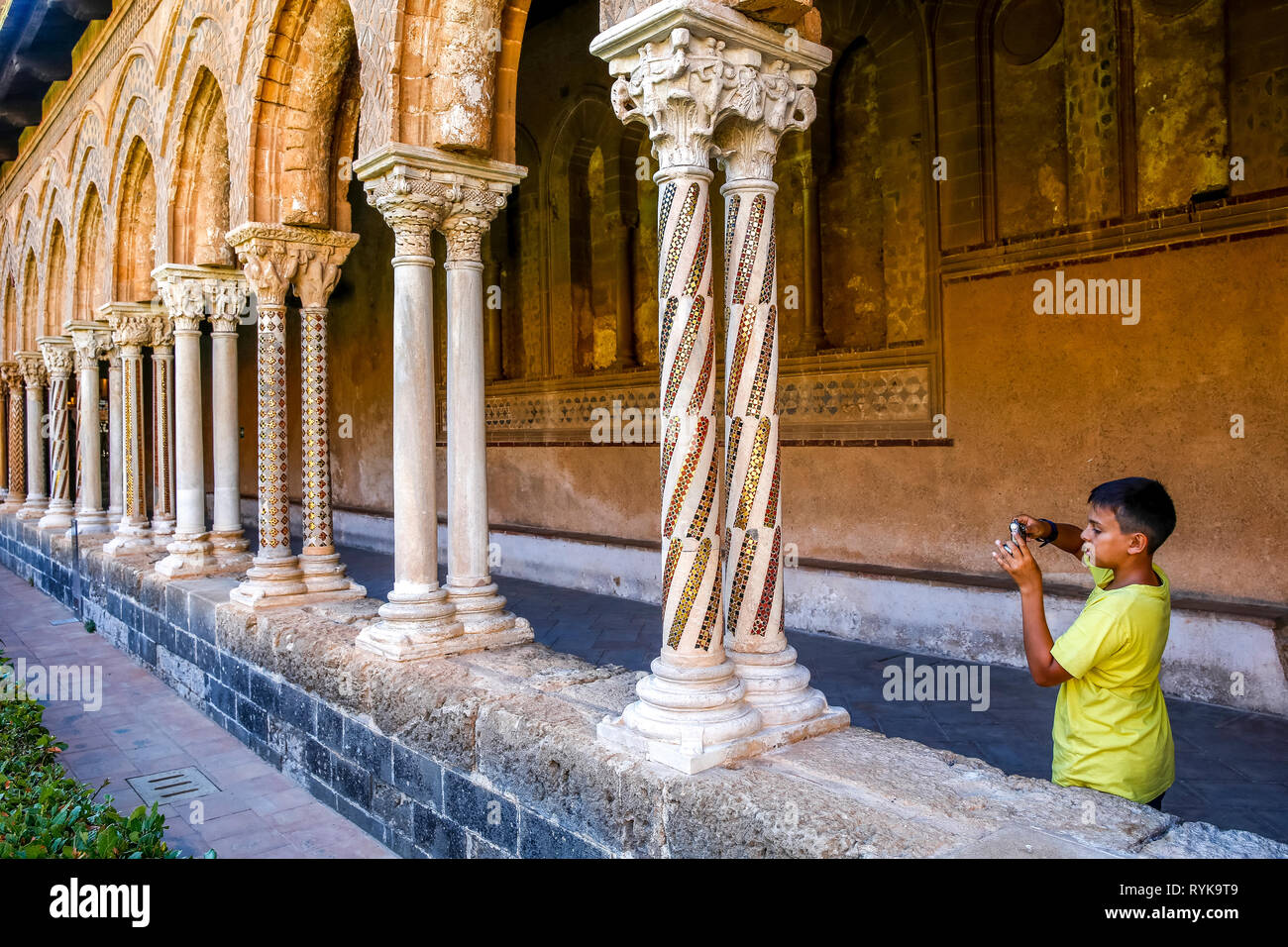 12-year-old boy taking a photograph in the cloister of Monreale cathedral, Sicily (Italy). Stock Photo
