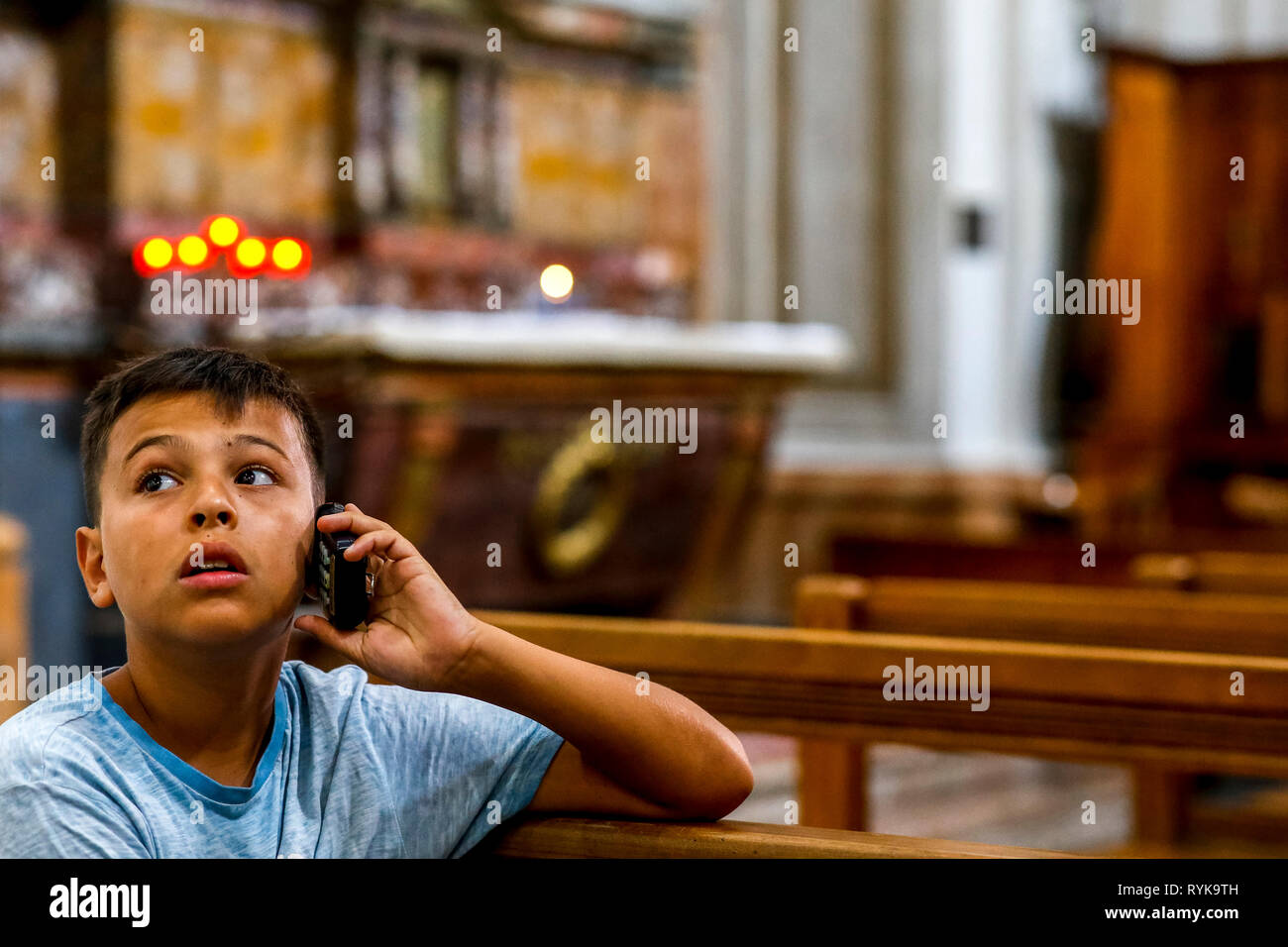 12-year-old boy using an audioguide in a church in Catania, Sicily (Italy). Stock Photo