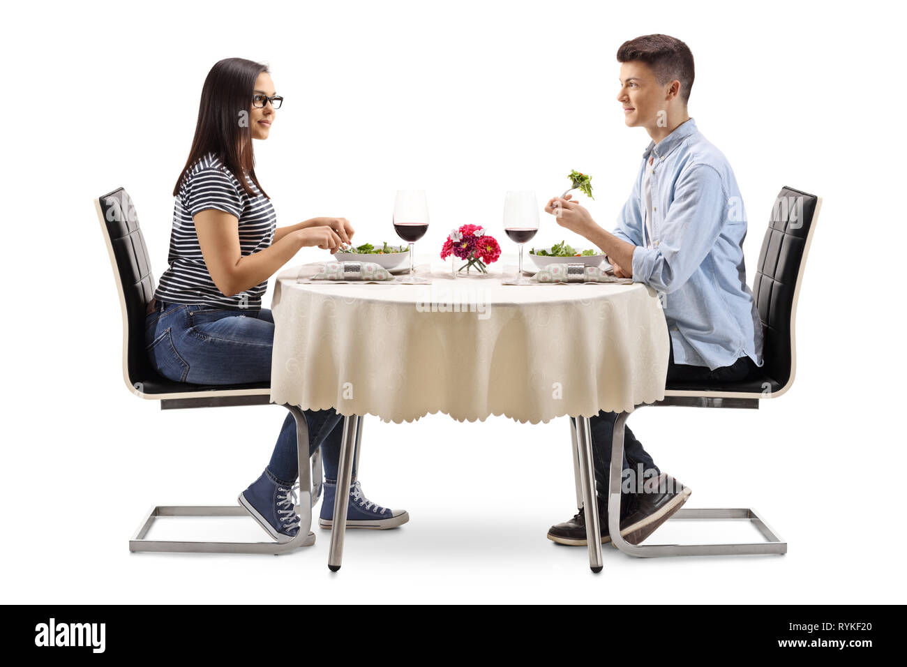 Full length profile of a young male and female eating a salad in a restaurant isolated on white background Stock Photo