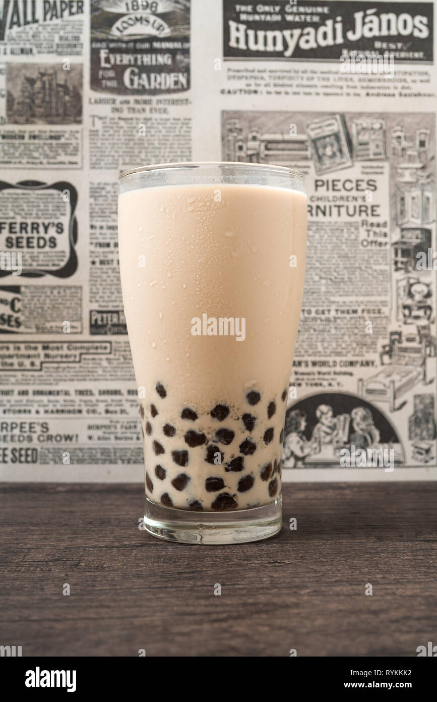 A glass cup of pearl milk tea (also called bubble tea) and a plate of ...