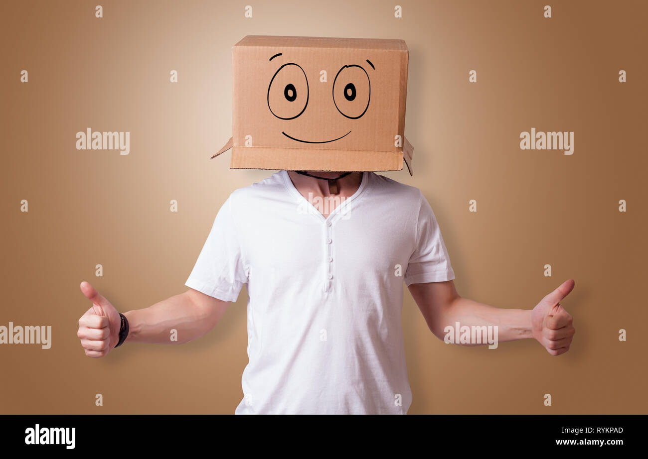 Young man standing and gesturing with a cardboard box on his head with ...