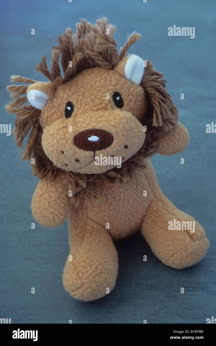 Soft cuddly stuffed toy model of light brown lion with dark brown mane sitting on marble sheet Stock Photo