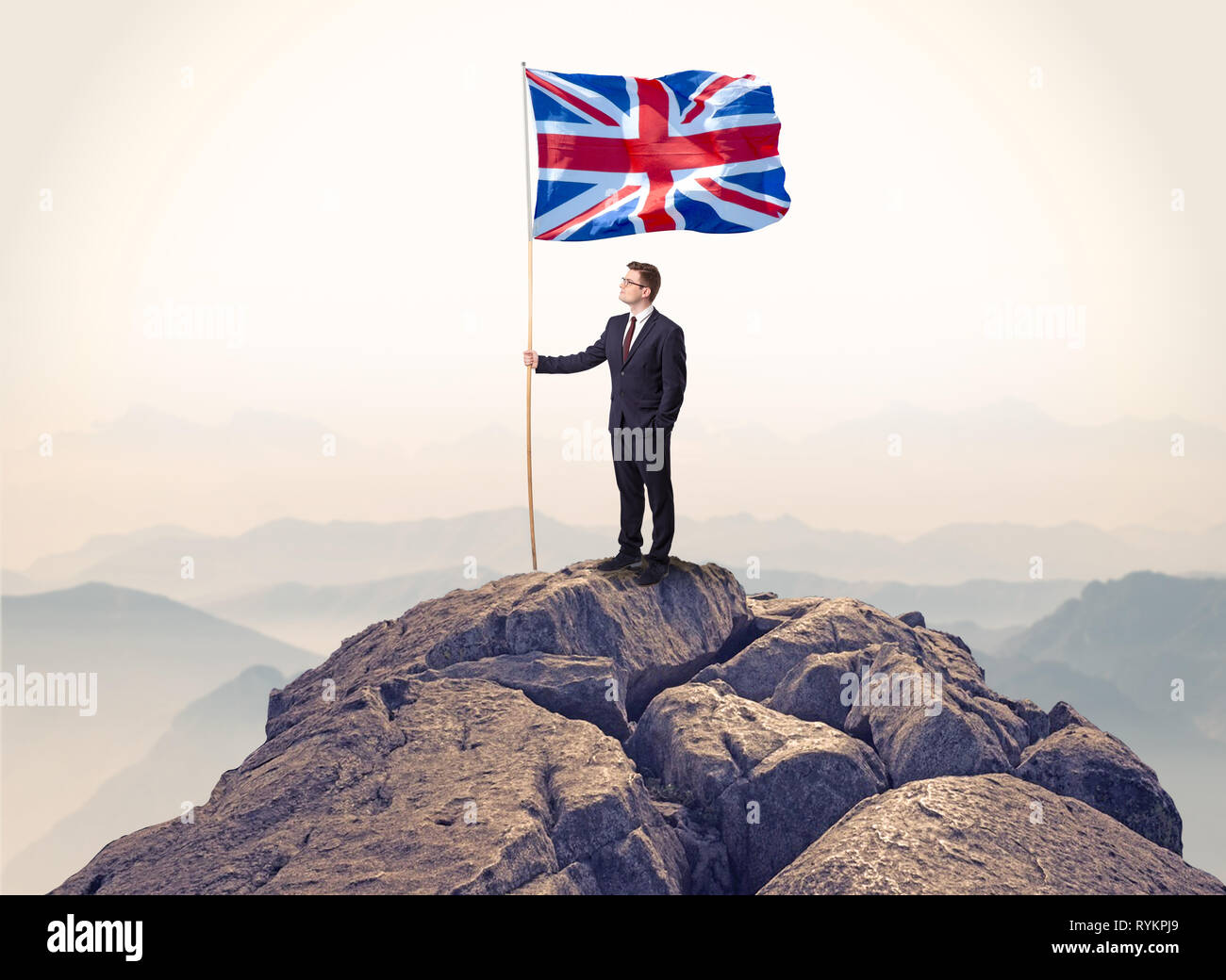 Successful businessman on the top of a mountain holding victory flag ...