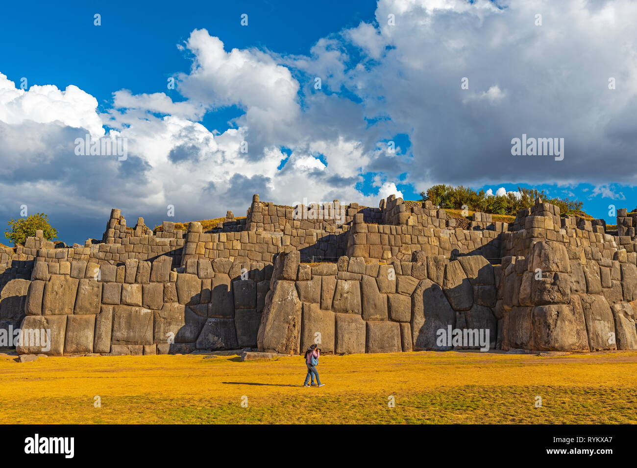 A couple walking along the giant granite inca wall of Sacsayhuaman in Cusco at sunset, Peru. Stock Photo