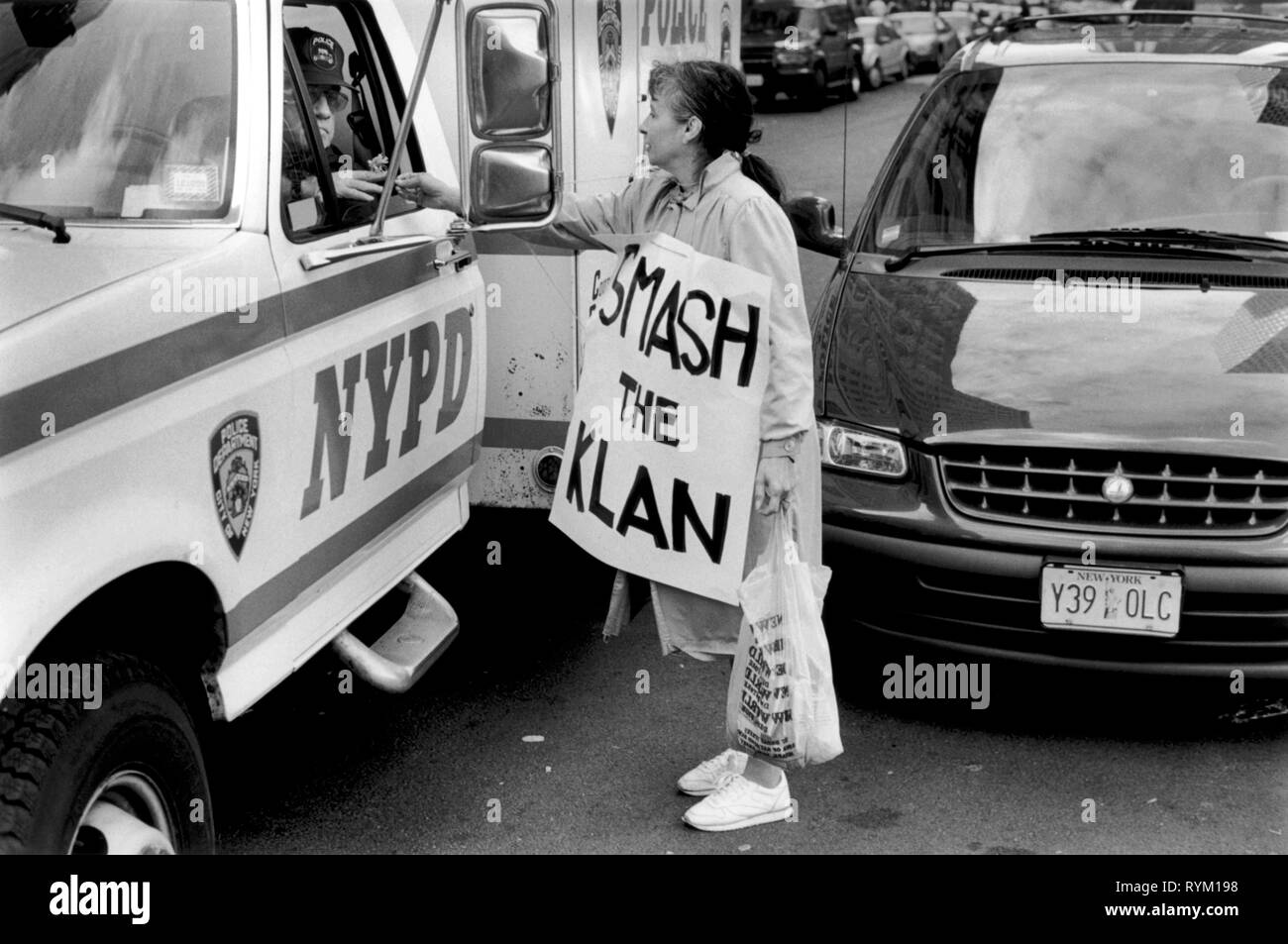 Anti Klu Klux Klan rally woman hands a flower to NYPD New York policeman who is sitting in his police van. She is wearing a smash the Klan banner around her neck. New York June 1990s. Manhattan New York USA June 1999  HOMER SYKES Stock Photo