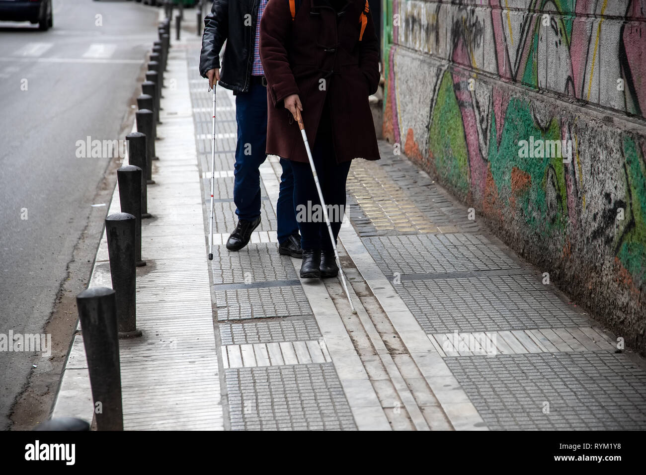blind man and woman walking on the street using a white walking stick Stock Photo Alamy