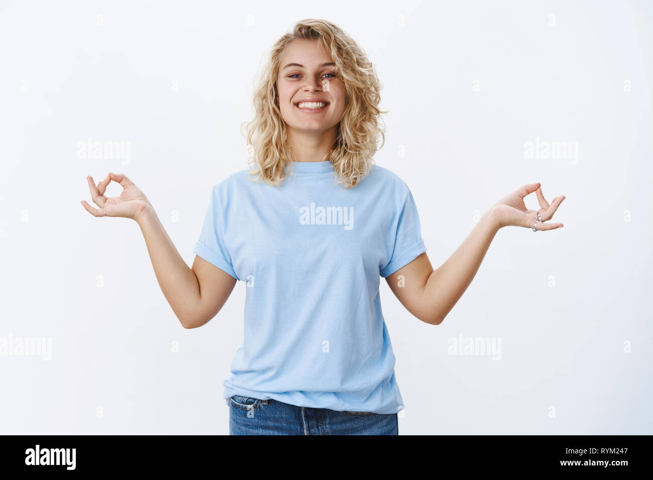 Keep calm and carry on. Portrait of optimistic relieved and stress-free good-looking female with blond hair smiling pleased and relaxed, standing in Stock Photo