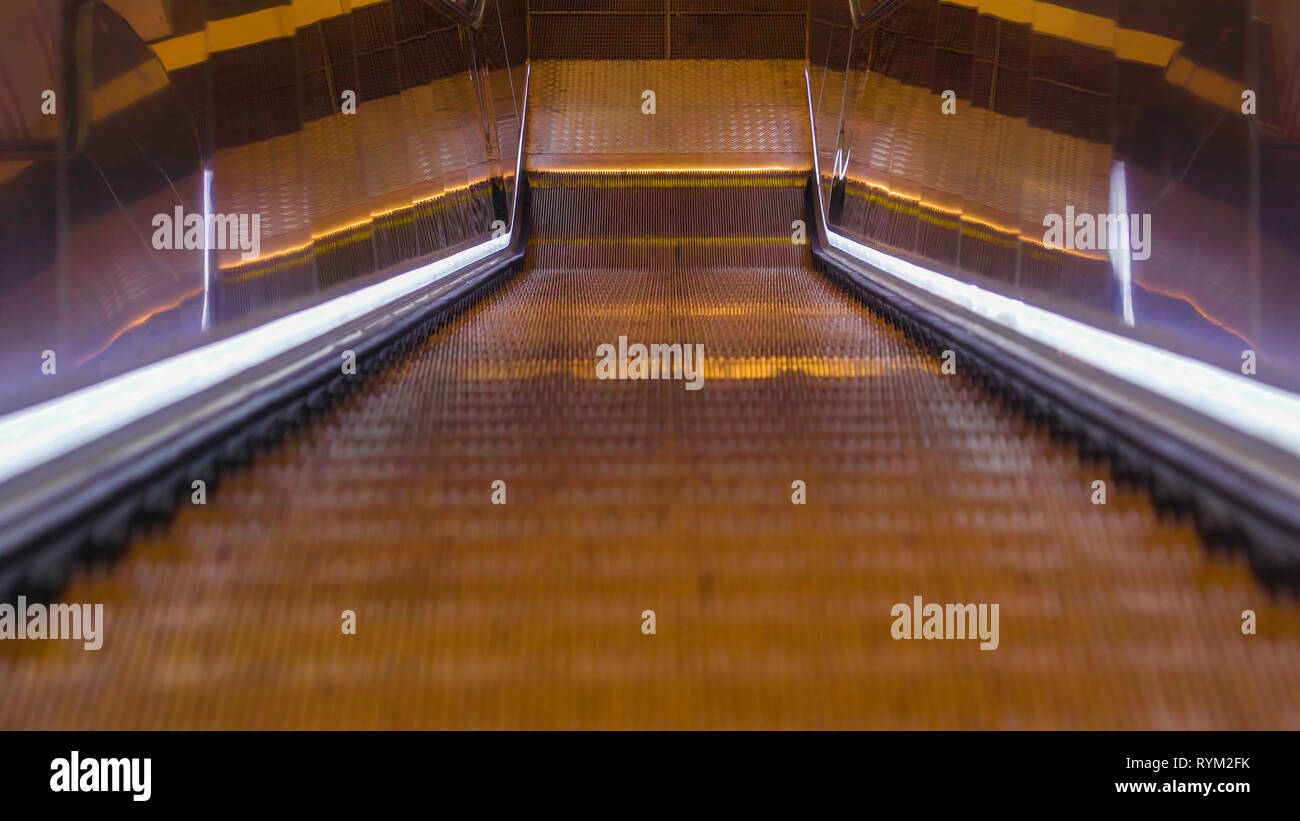 An escalator of a building with the moving stairs and the side railings ...