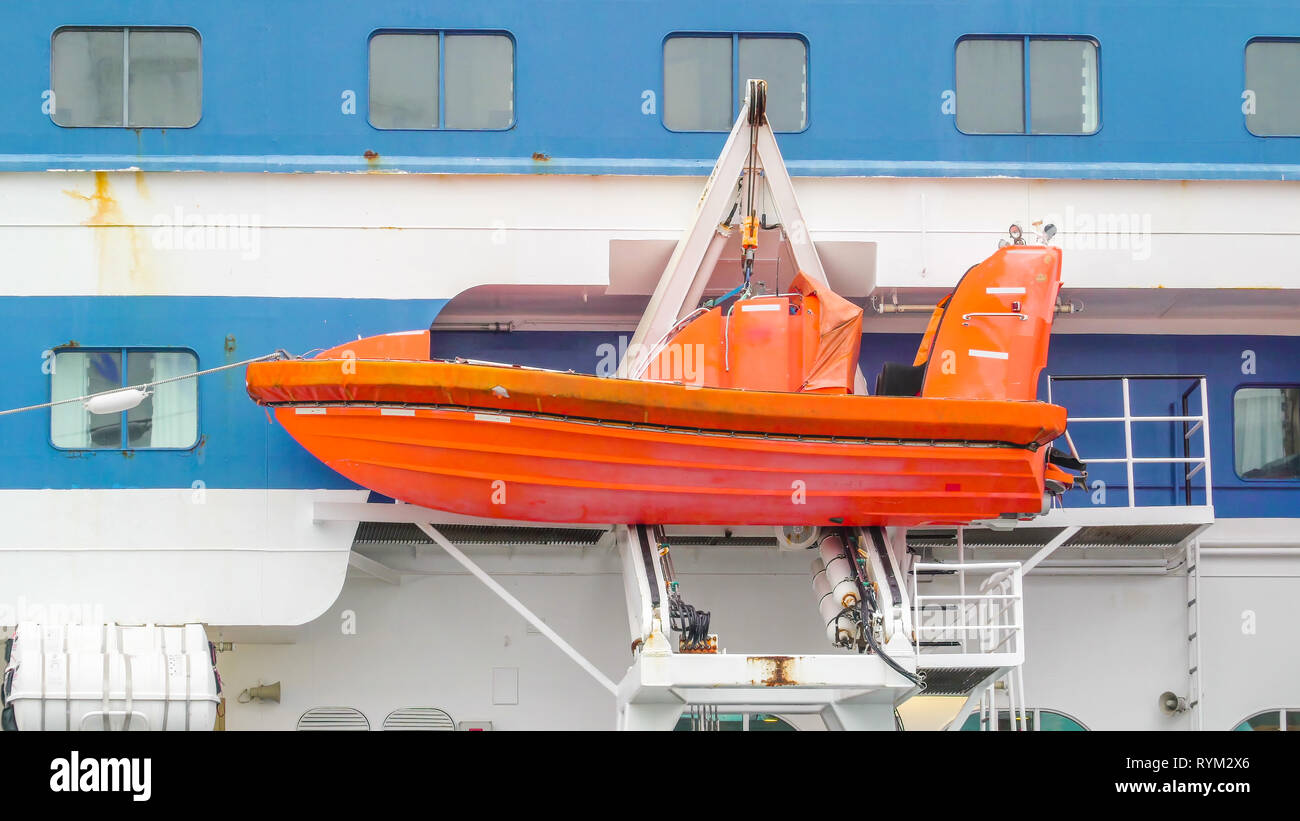 An orange speedboat on the side of the cruise ship in Stockholm Sweden while on dock on the port Stock Photo