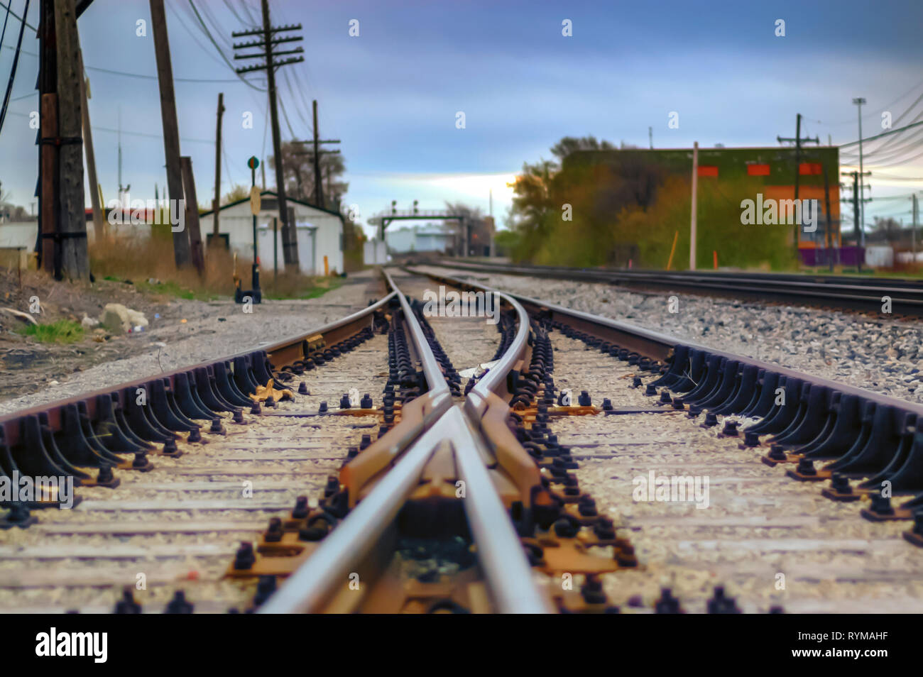 A low angle shot of railway tracks curving & disappearing into the distance. A railroad switch or turnout to enable trains to switch tracks is visible. Stock Photo