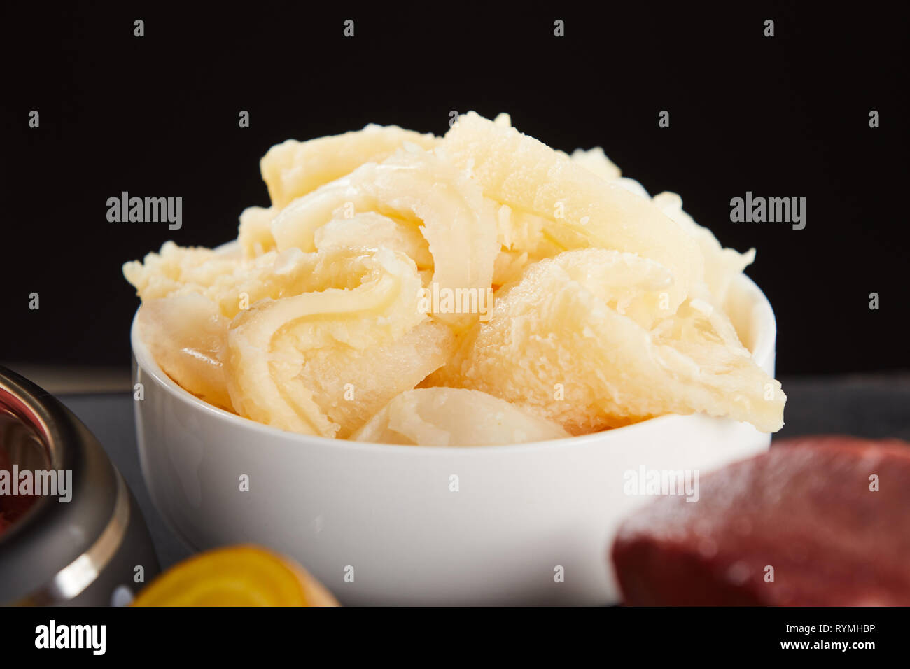 Raw beef stomach pieces in white bowl, viewed in close-up against black background. Preparing food for dogs ingredients Stock Photo