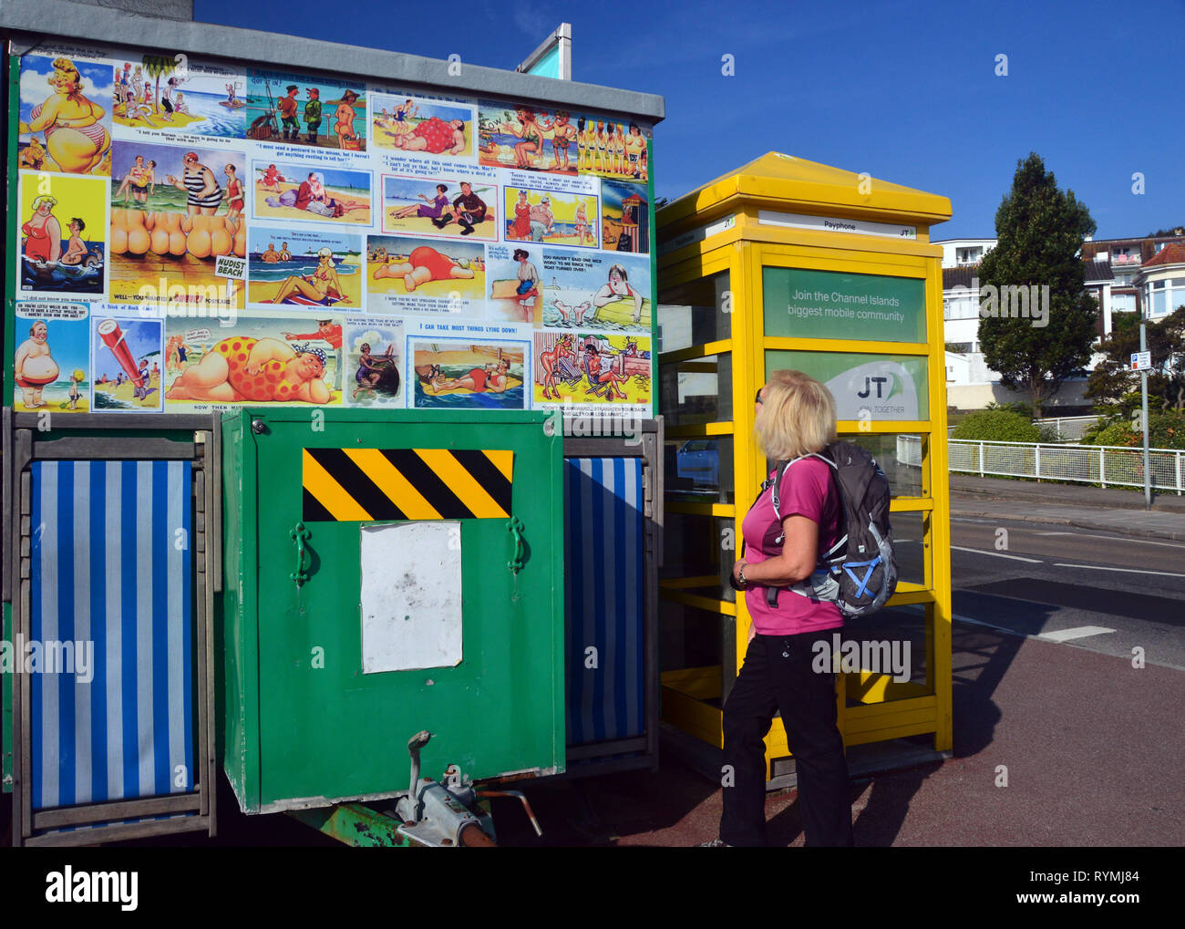 Woman Hiker Looking at Cheeky Postcards on Tea Van next to a Yellow Phone Box near St Helier on the Island of Jersey, Channel Isles, UK. Stock Photo