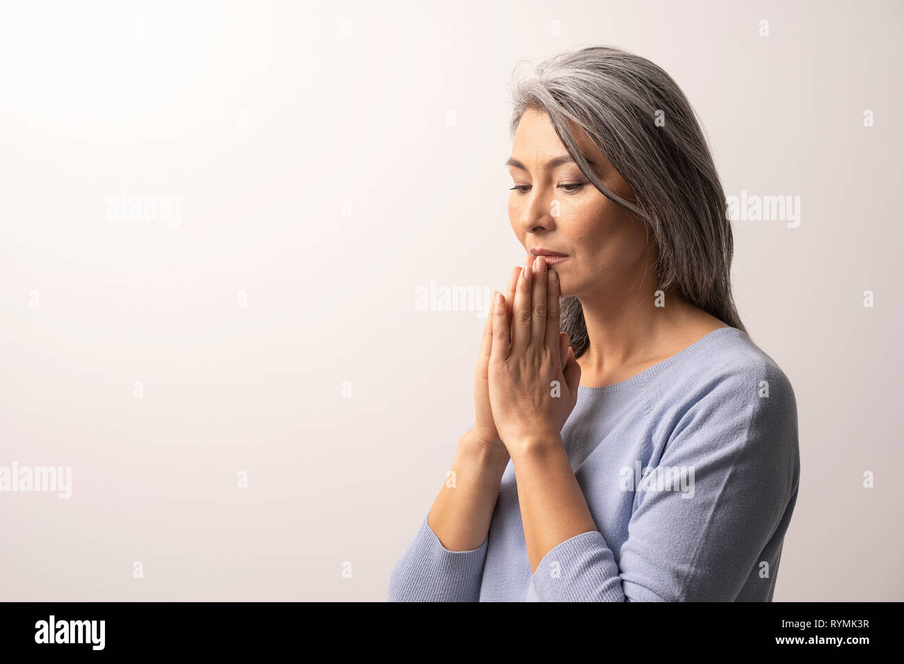 Mature Asian woman praying on white background Stock Photo