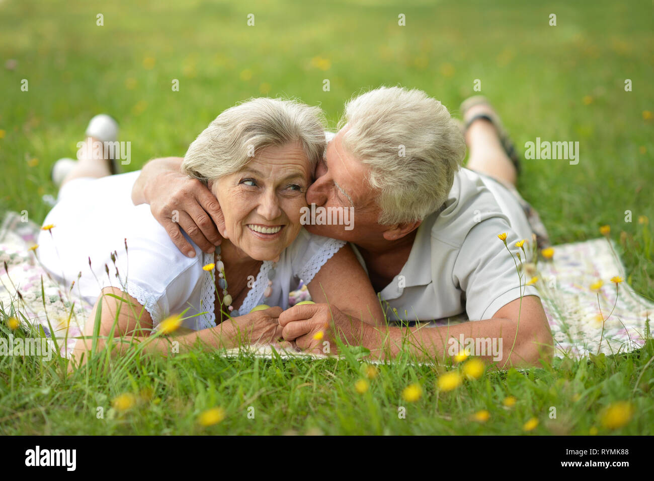 Portrait of happy senior couple lying in summer park Stock Photo