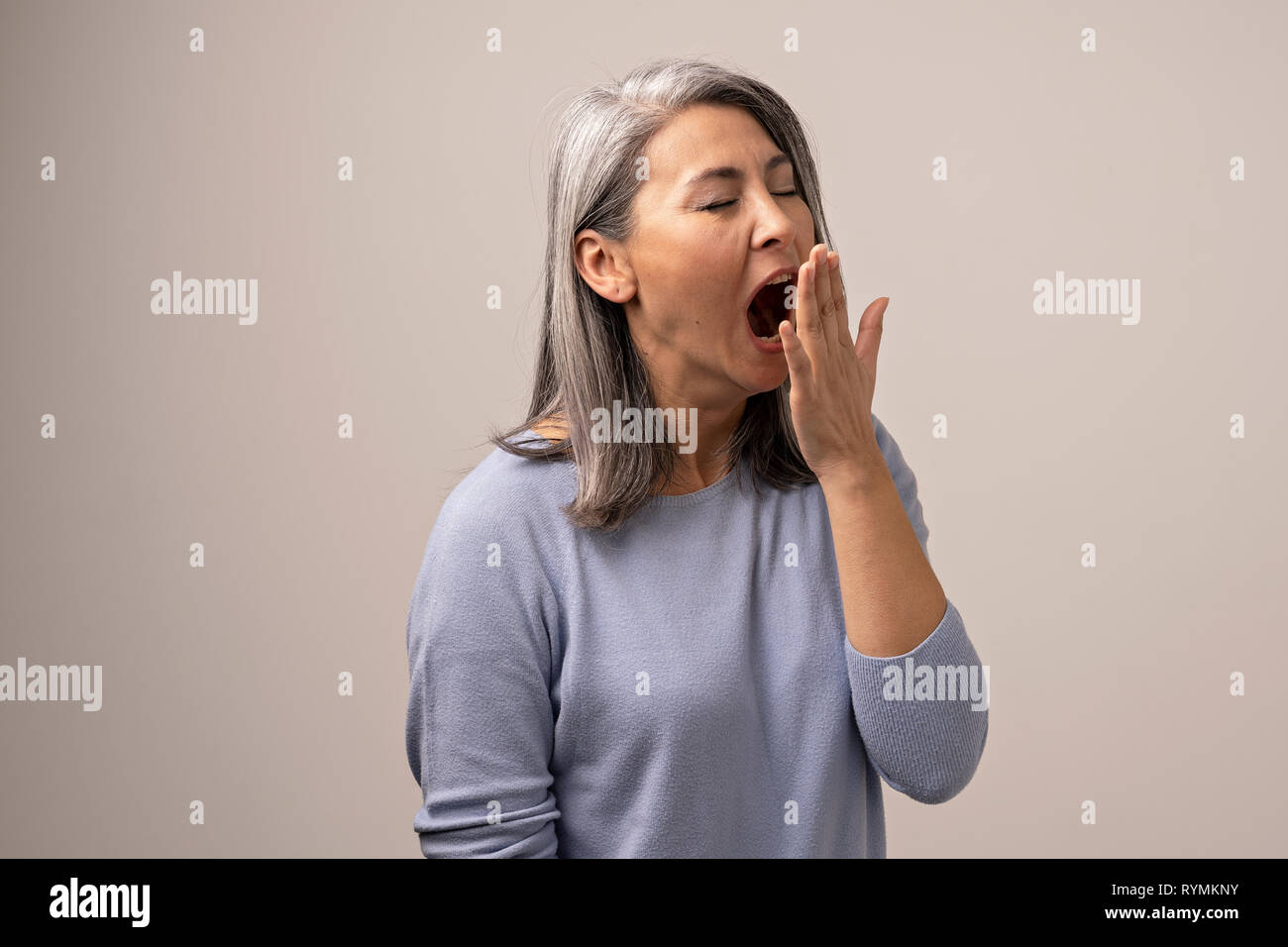 Tired Asian woman yawning in photo studio Stock Photo