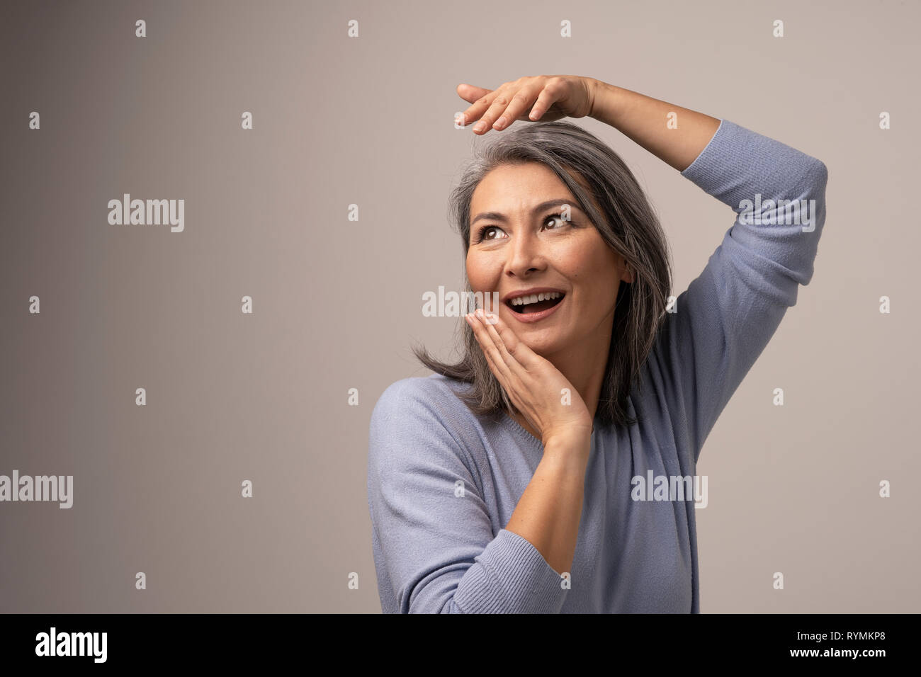 Happy Woman with Gray Hair Mongolian Appearance on Gray Background. Stock Photo