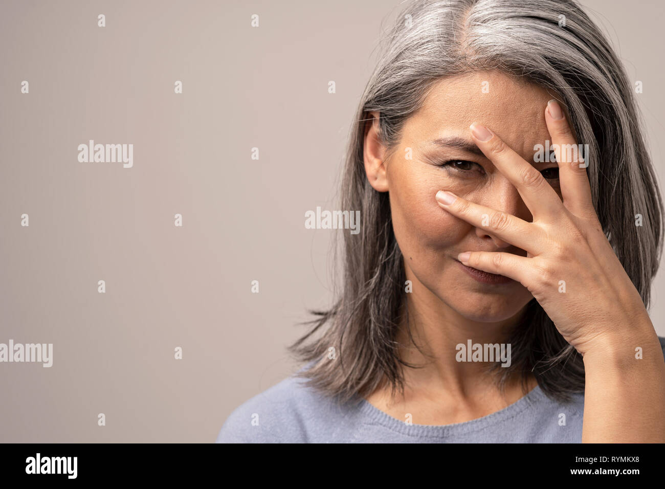 Beautiful woman is peeping through her fingers Stock Photo