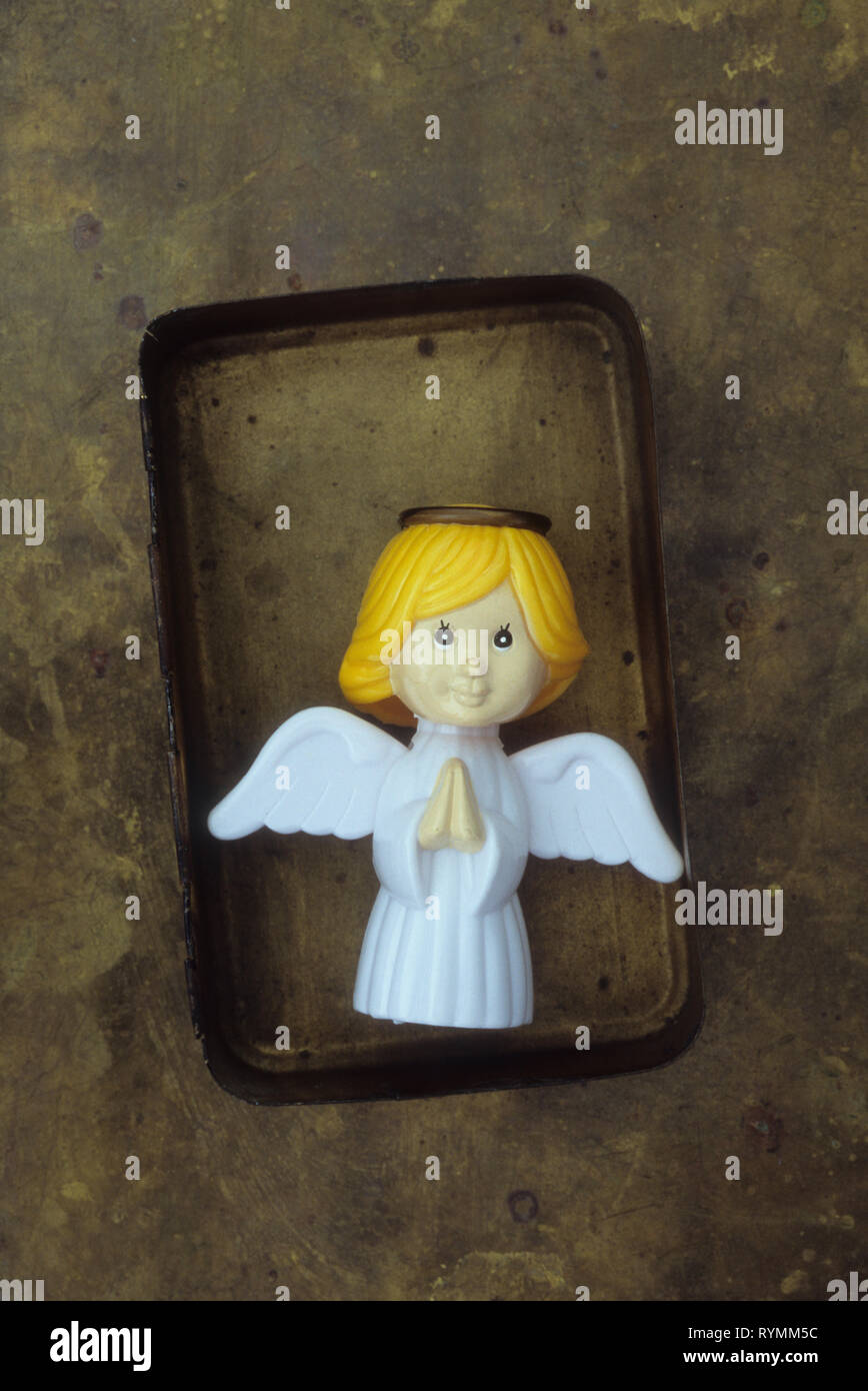 Plastic model of modern angel with hands clasped in prayer lying in tarnished brass box Stock Photo