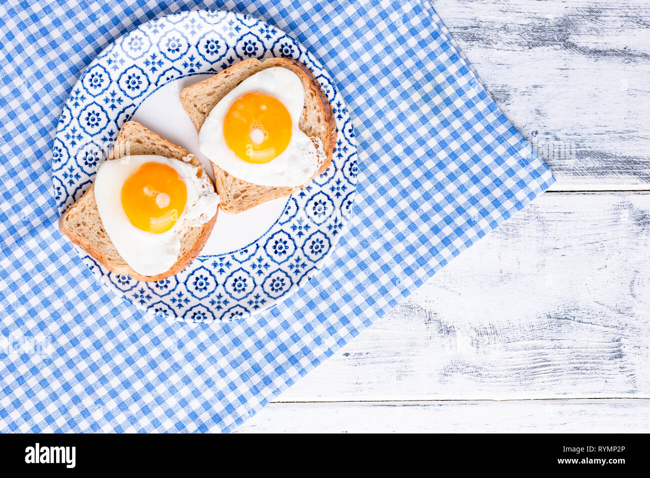 Breakfast of 2 fried heart shaped eggs. Romantic morning surpriiz on holiday. Valentine's day concept. Copy space, Flat lay Stock Photo