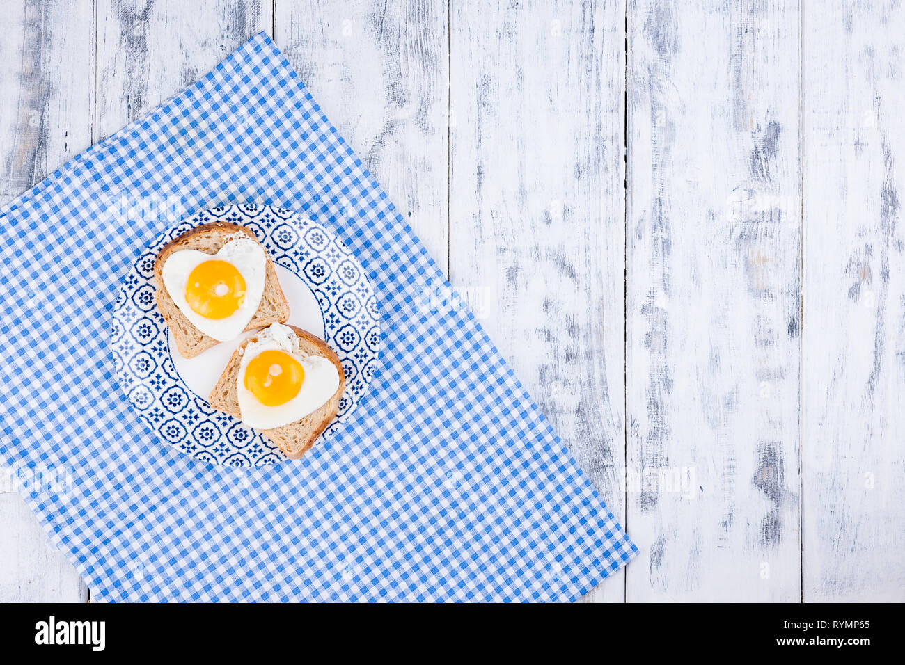 Breakfast of 2 fried heart shaped eggs. Romantic morning surpriiz on holiday. Valentine's day concept. Copy space, Flat lay Stock Photo