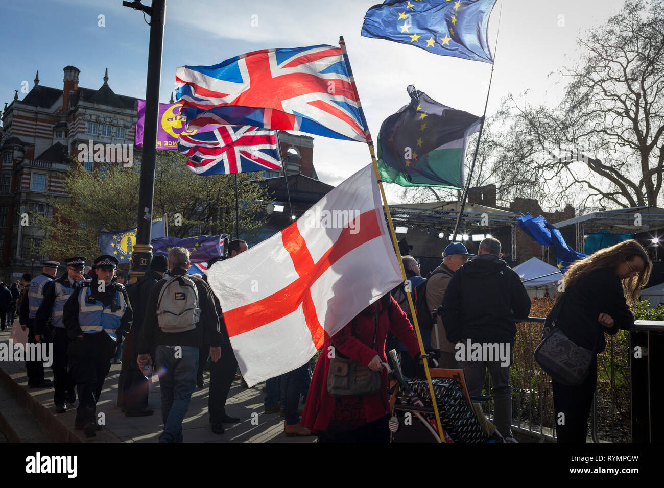 On the day that MPs in Parliament vote on a possible delay on Article 50 on EU Brexit negotiations by Prime Minister Theresa May, the British Union jack, the English Cros of St. George and the EU flag fly over College Green during a protest outside the House of Commons, on 14th March 2019, in Westminster, London, England. Stock Photo