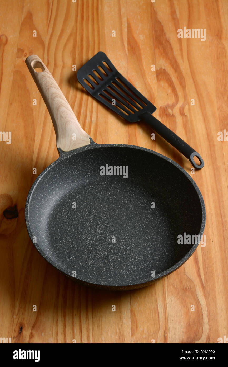 New non-stick frying pan on wooden table - closeup Stock Photo