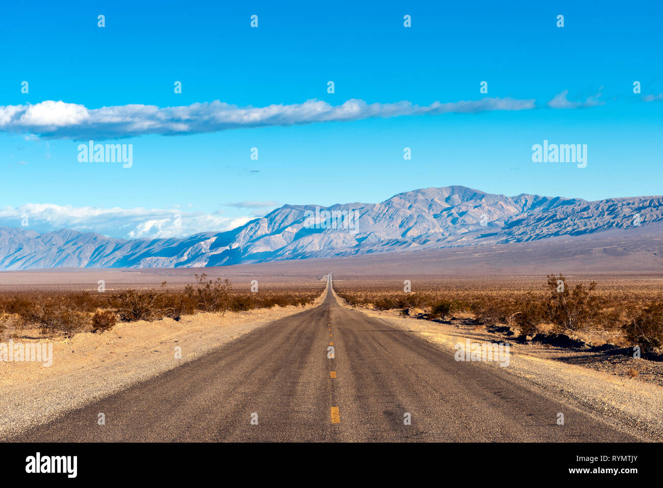 Looking down the middle of a long straight desert road with no one in site for miles. Stock Photo