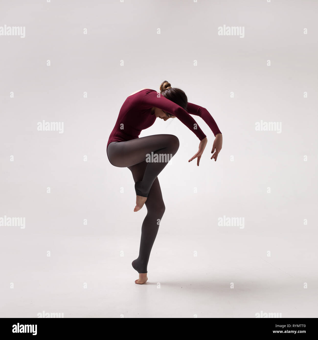 young woman dancer in maroon swimsuit jumping Stock Photo