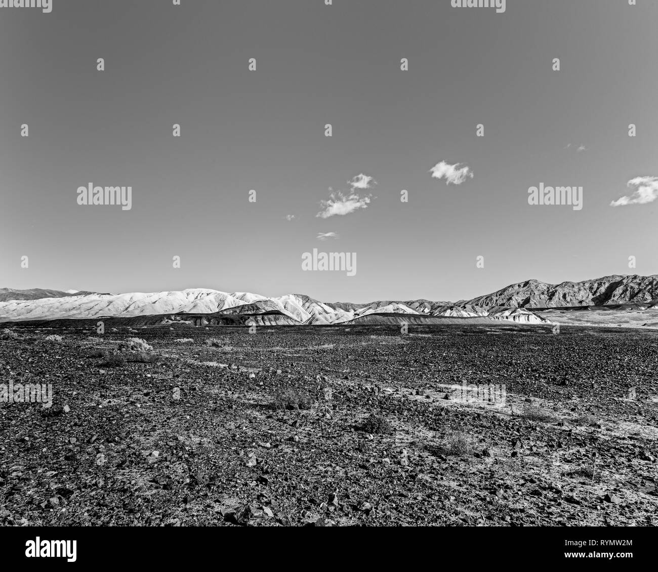Rocky desert field with white barren mountain beyond. Stock Photo
