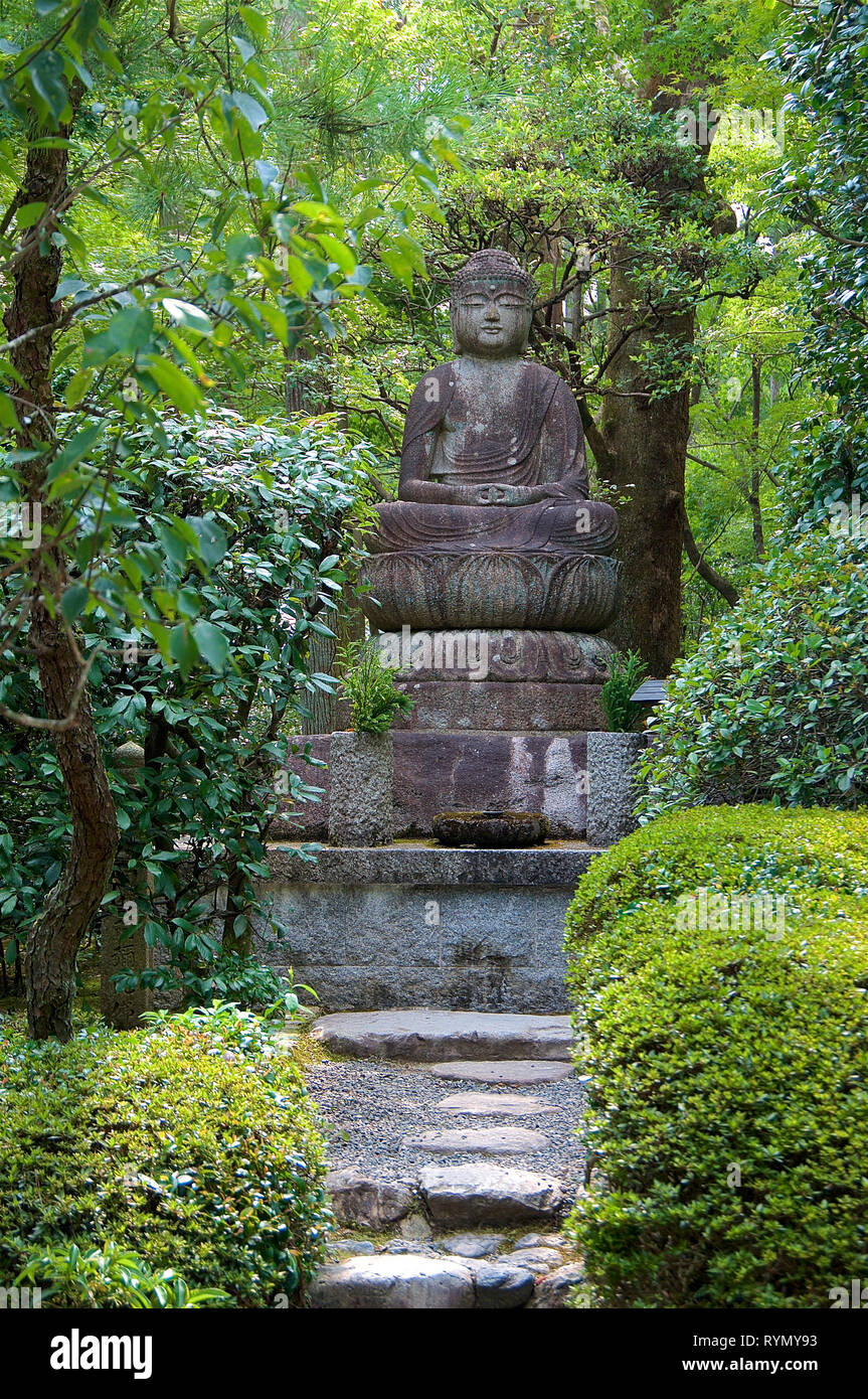 Beautiful and peaceful Buddha statue surrounded in the lush green nature of the Ryōan-ji Temple in Kyoto, Japan Stock Photo