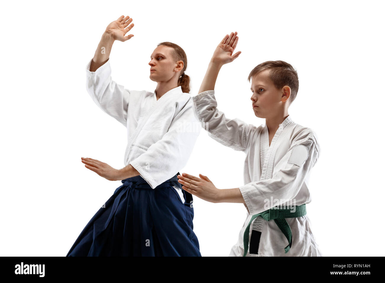 Man and woman fighting at Aikido training in martial arts school. Healthy lifestyle and sports concept. Man with beard in white kimono on white background. Karate woman with a concentrated face. Stock Photo