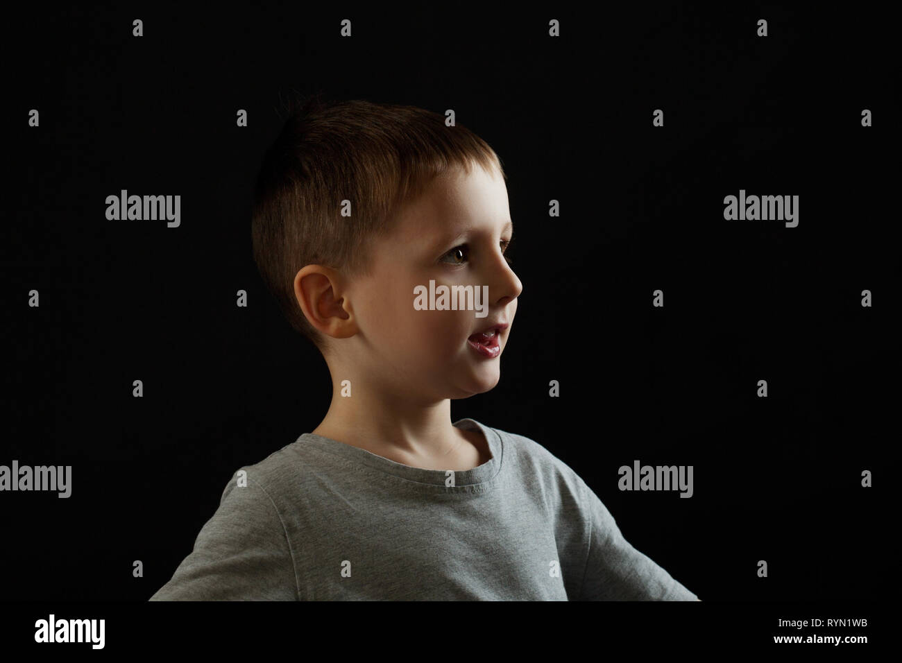 Portrait of a child in profile on a black background. Boy looking forward, concept, copy space right Stock Photo