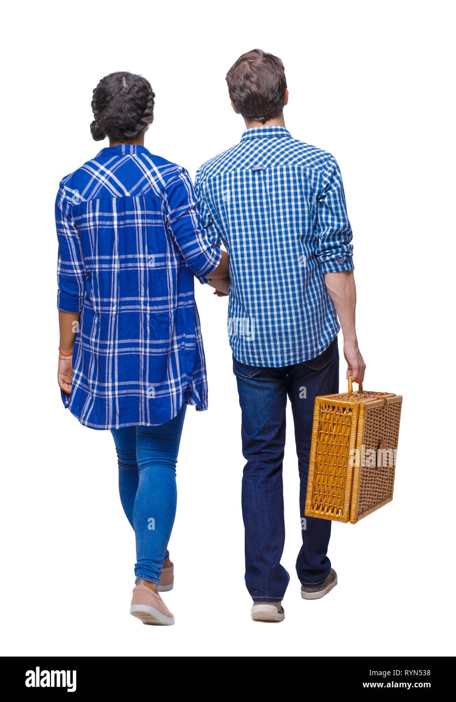 Back view of interracial going couple with a picnic bag. walking friendly girl and guy holding hands. Rear view people collection. backside view of pe Stock Photo