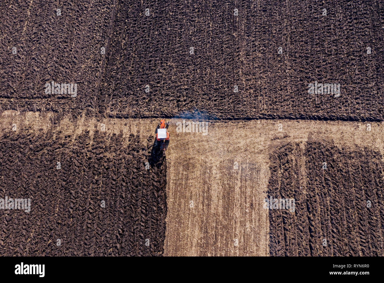 Aerial top view of a tractor, combine harvester plowing agricultural ...