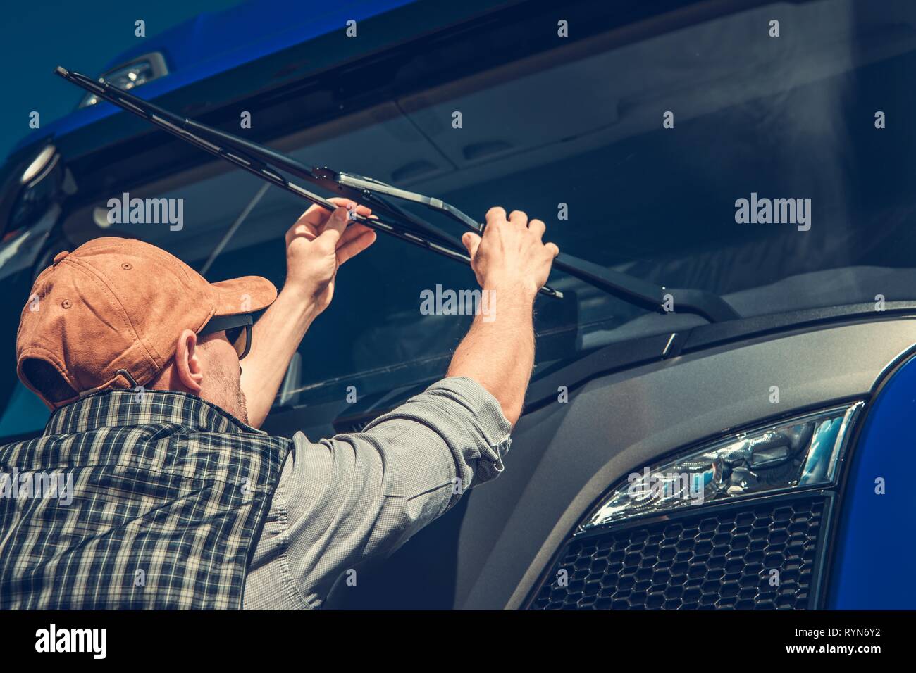 Truck Wipers Replacement by Caucasian Semi Truck Driver. Automotive Industry. Stock Photo