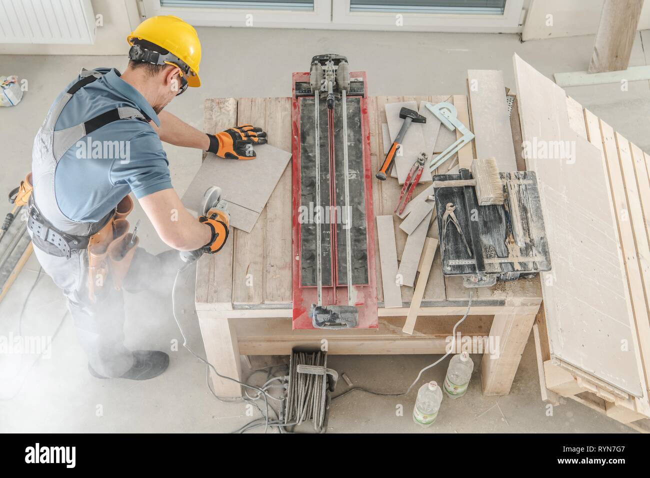 Caucasian Construction Worker and His Workplace. Men Cutting Ceramic Tiles. Stock Photo