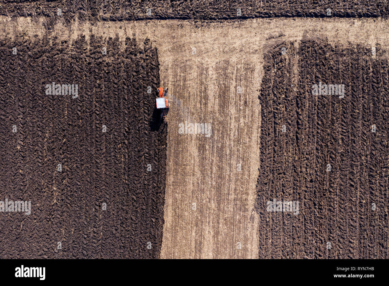 Aerial top view of a tractor, combine harvester plowing agricultural ...