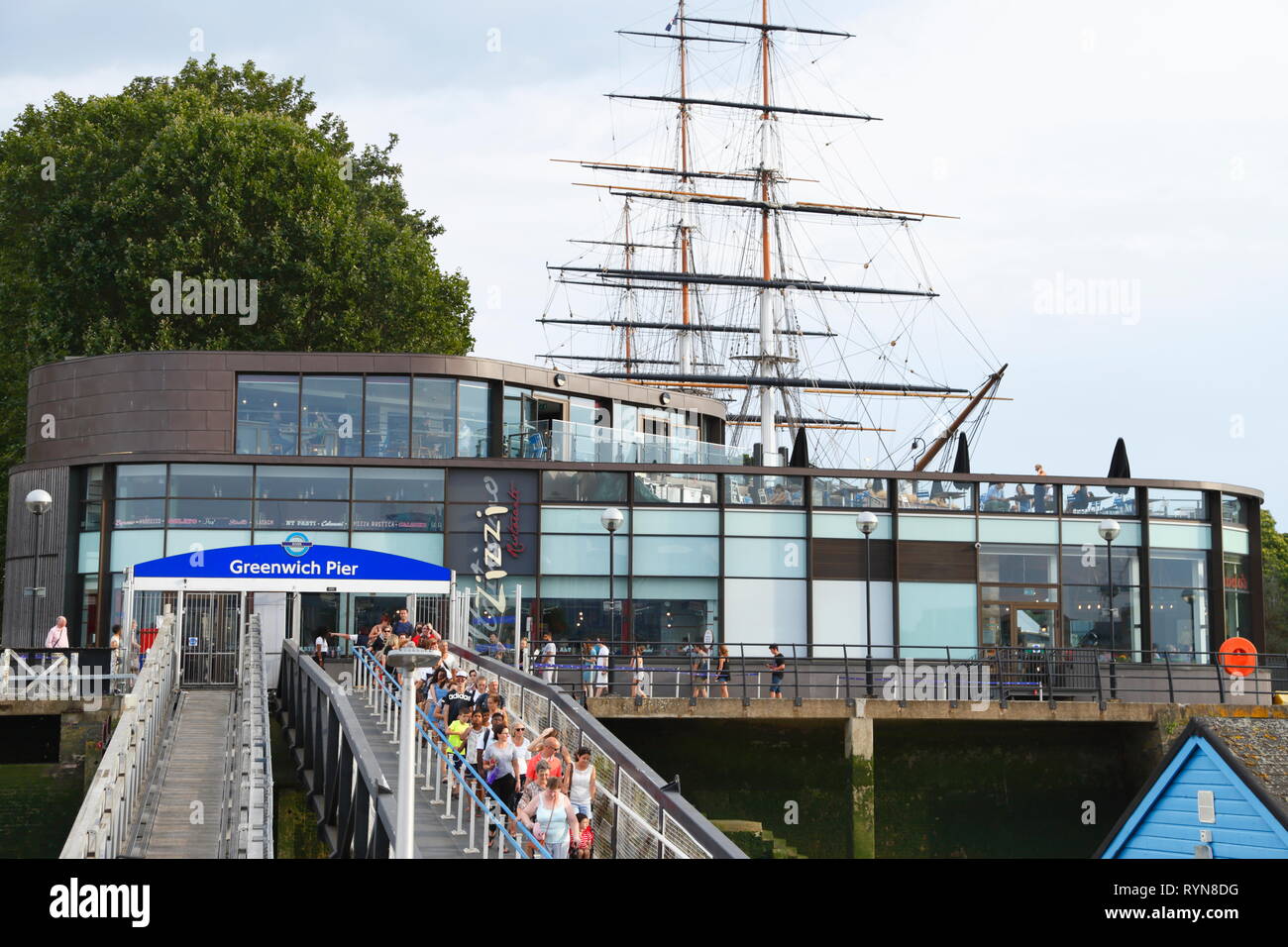 Passengers walk over a bridge to a boat on the River Thames, at Greenwich Pier in London, United Kingdom. Stock Photo