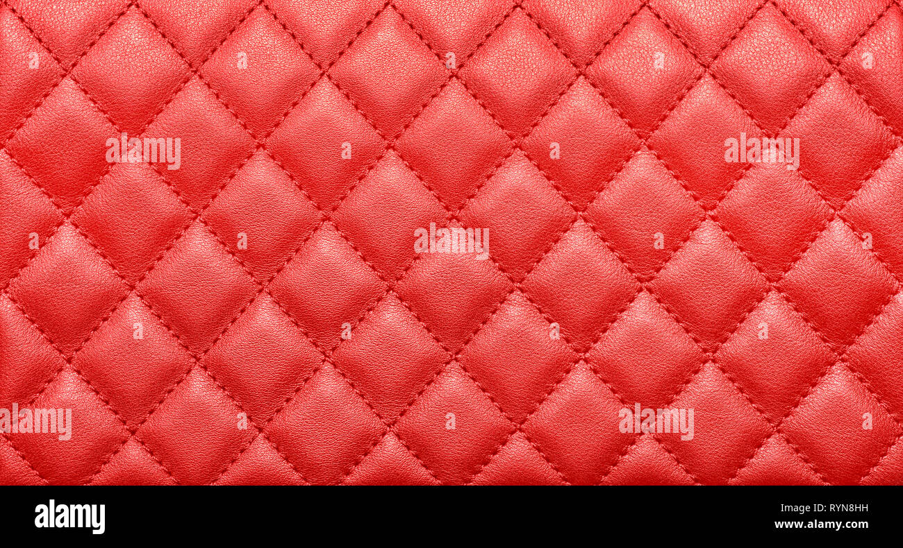 Close-up texture of genuine leather with rhombic stitching. Saturated red color. Luxury background Stock Photo
