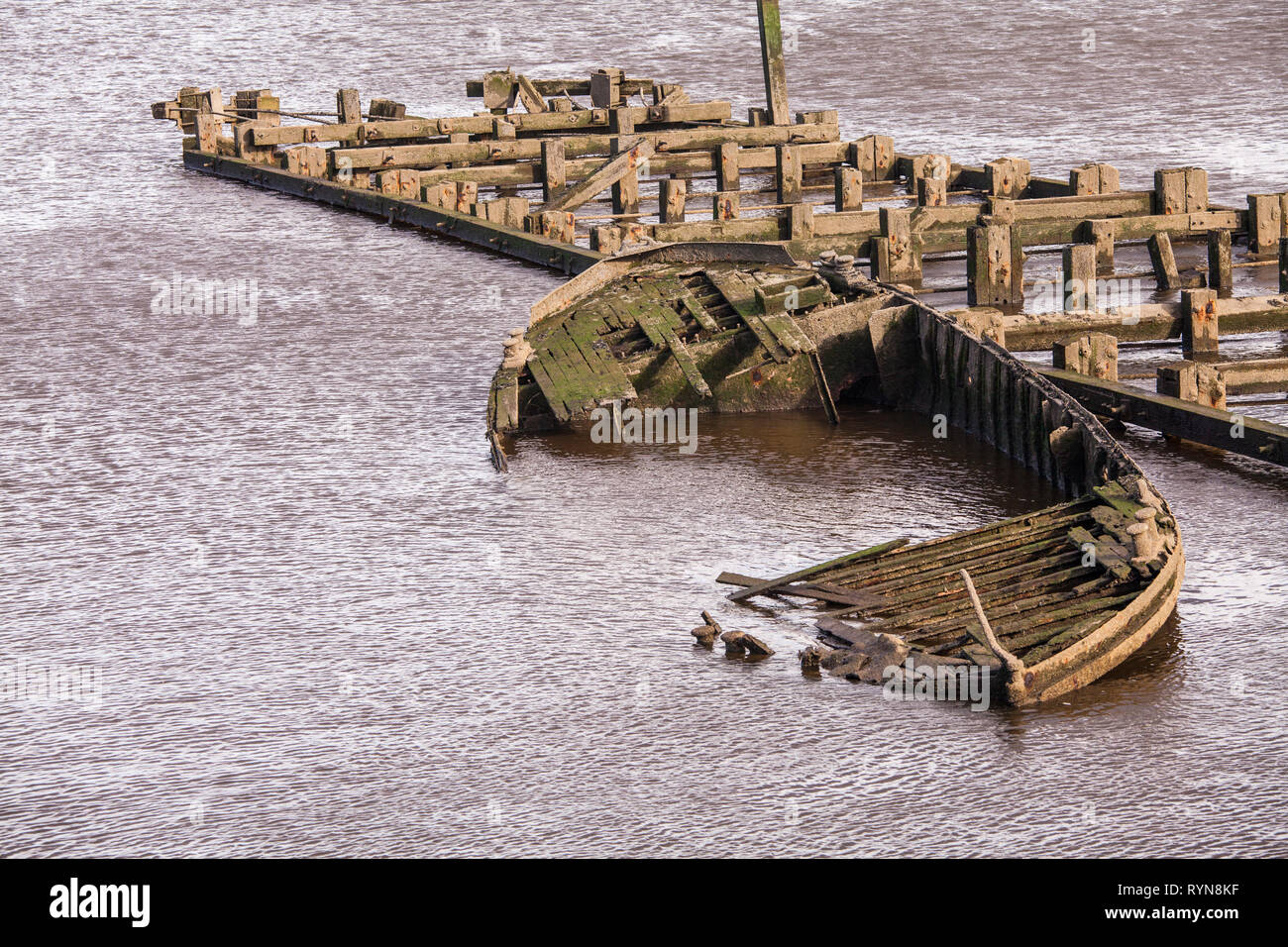 A sunken rowing boat  and a wooden jetty in the River Tees at Middlehaven, Middlesbrough, England,UK Stock Photo