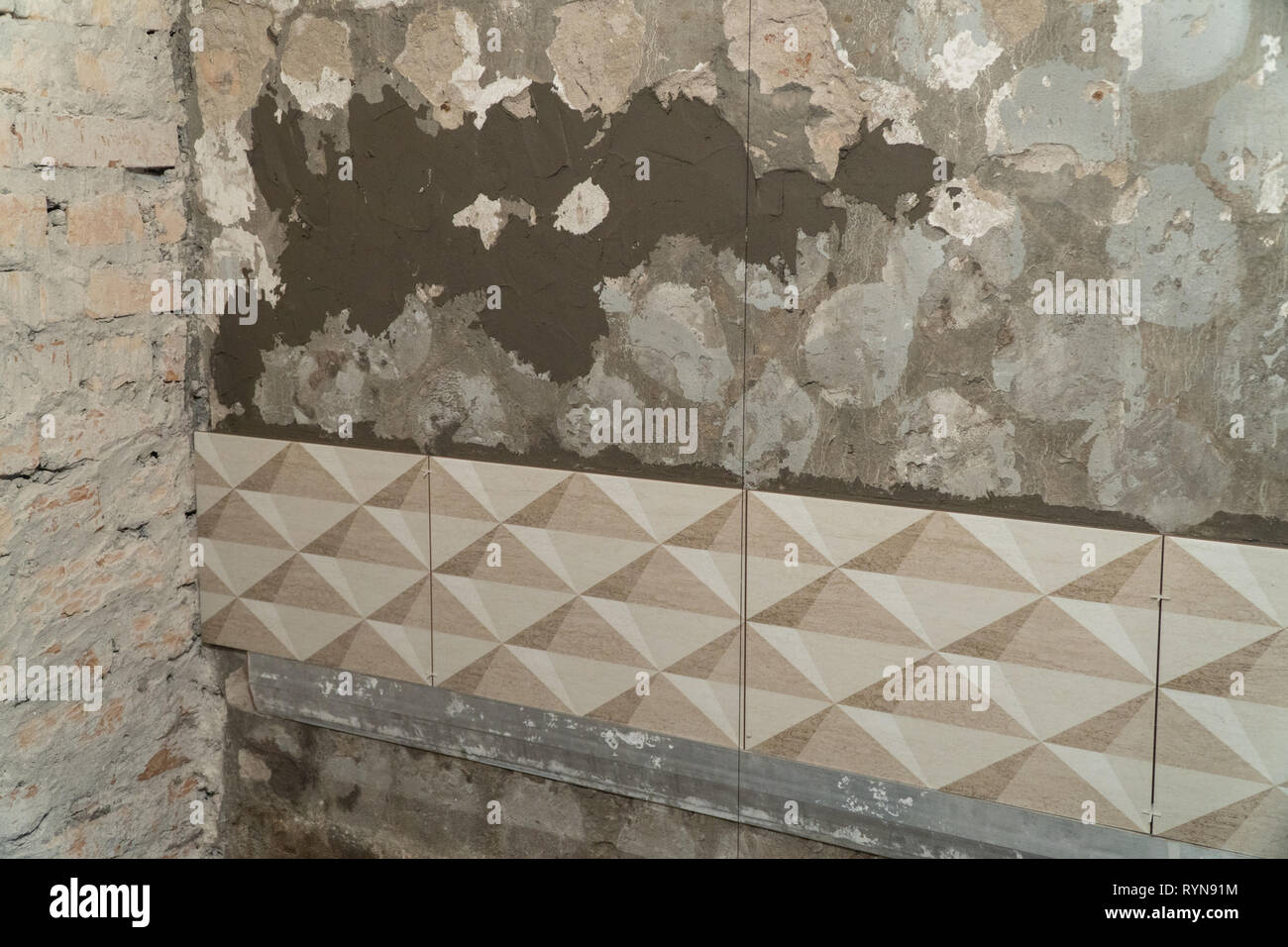 The process of installation of decorative tiles on the wall in the
