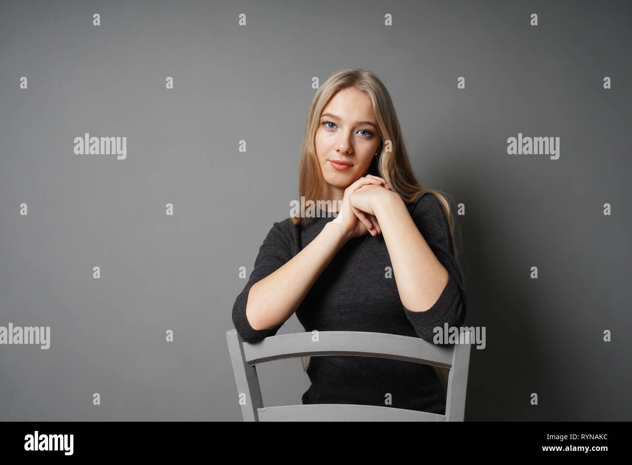 serene young woman sitting astride on chair Stock Photo