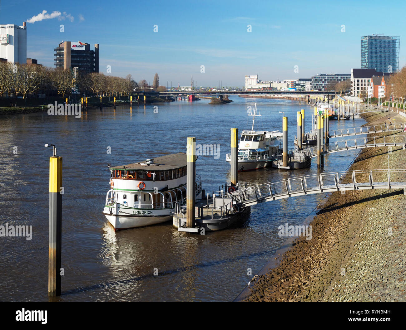 Bremen, Germany - February 24th, 2019 - Pier with several moored vessels with Weser Tower and Beck's brewery in the background Stock Photo