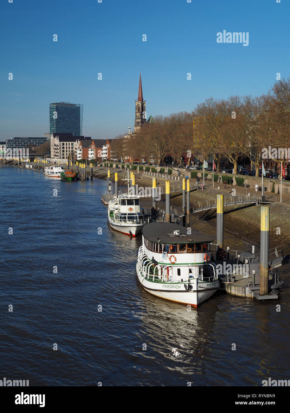 Bremen, Germany - February 24th, 2019 - Pier with several moored vessels with Weser Tower and St. Stephani church in the background Stock Photo