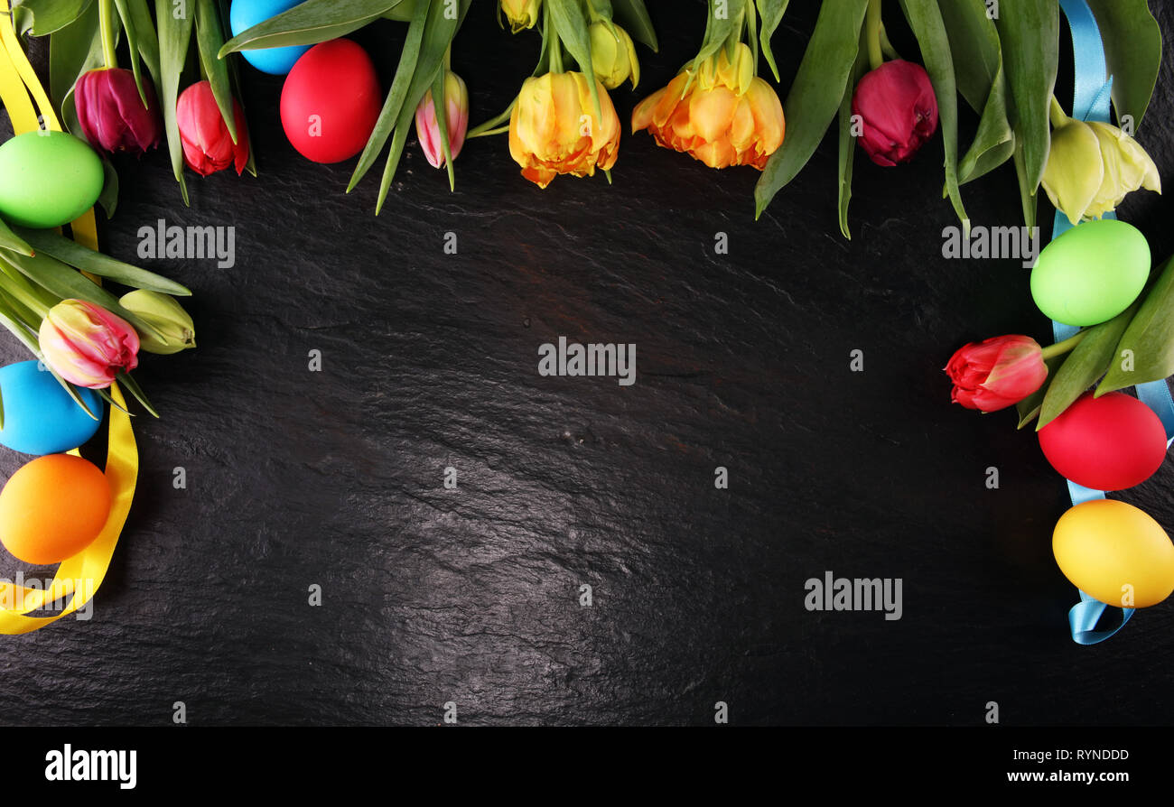 Easter eggs and colorful tulips on rustic table Stock Photo - Alamy