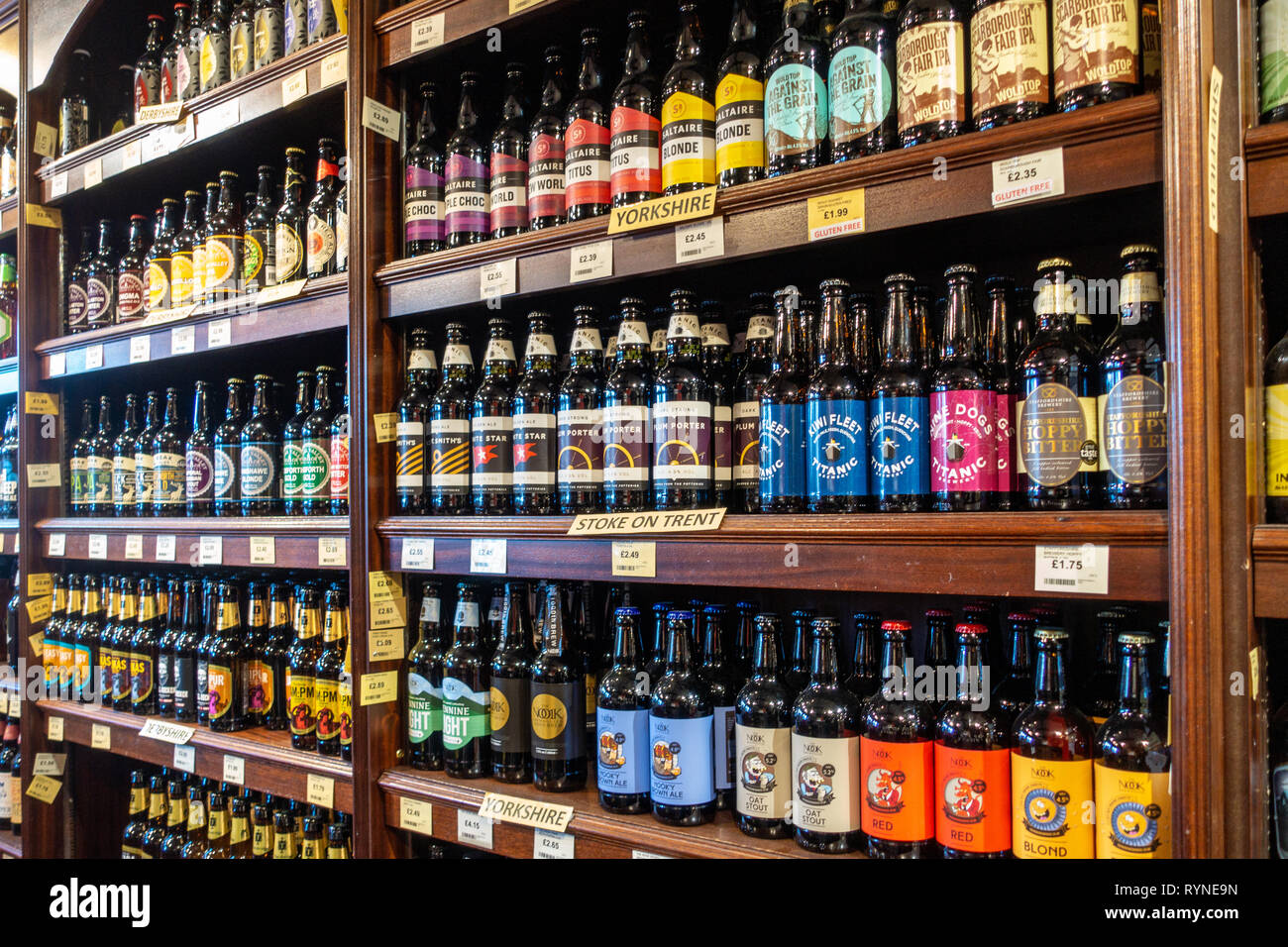 Close up photograph of bottled beers in neat and tidy rows on shelves in a local beer store, Off-Licence in the UK Stock Photo