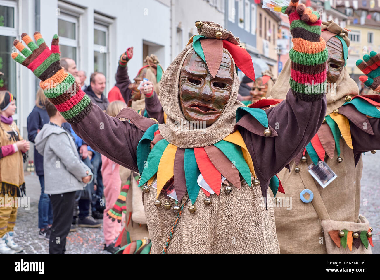 Carnival figure in a brown costume raises both arms. Street Carnival in Southern Germany - Black Forest. Stock Photo